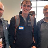 Three event attendees standing together and smiling for camera